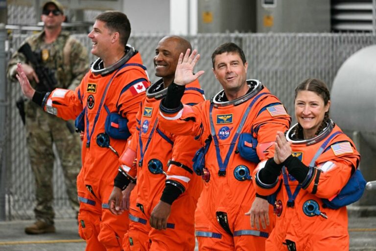 Los cuatro astronautas de la misión Artemis II de la NASA posan frente a un emblema de la misión.