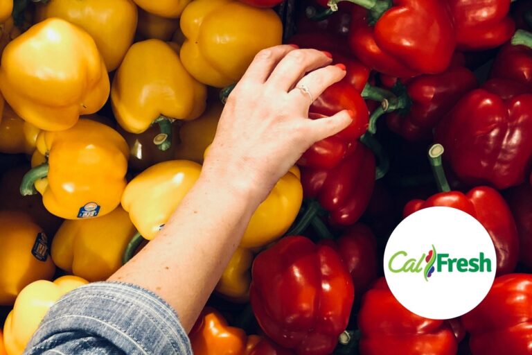 Tarjeta EBT de beneficios CalFresh sobre una mesa con alimentos.