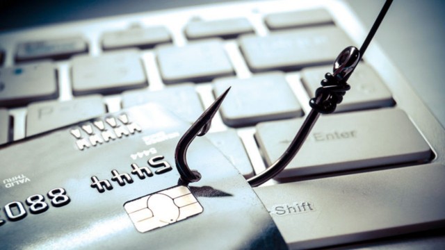 Persona usando una laptop con un símbolo de alerta de seguridad digital en la pantalla, representando el riesgo de phishing.