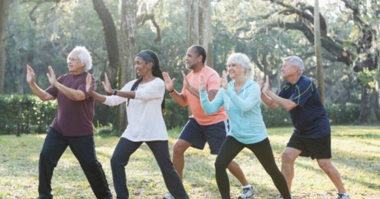 Persona mayor practicando Tai Chi en un parque, realizando movimientos suaves y fluidos.