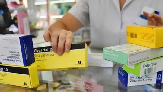 Persona mayor consultando información sobre medicamentos en una tablet, junto a su credencial de PAMI.