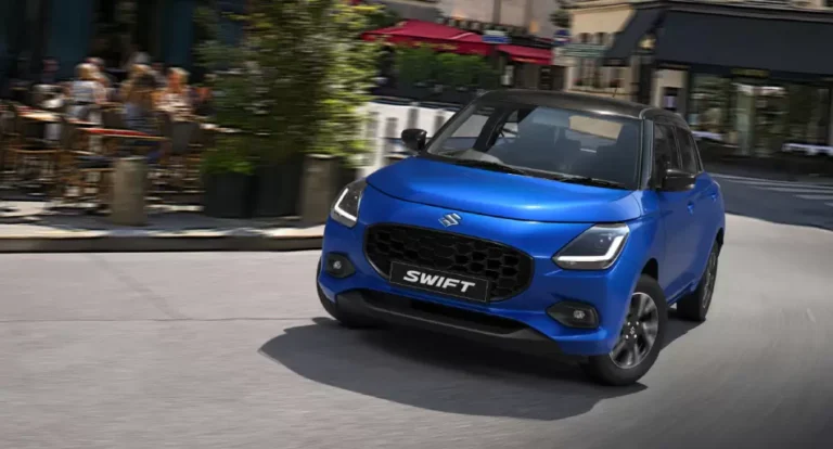 Nuevo Suzuki Swift Híbrido color Azul Metálico estacionado en ciudad, mostrando su diseño frontal renovado.